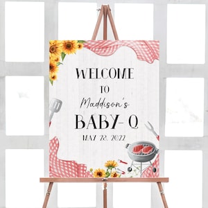 May include: Welcome to Maddison's Baby-Q sign with a white wood background, red and white checkered tablecloth, sunflowers, and barbecue grill with a spatula, tongs, and a steak.
