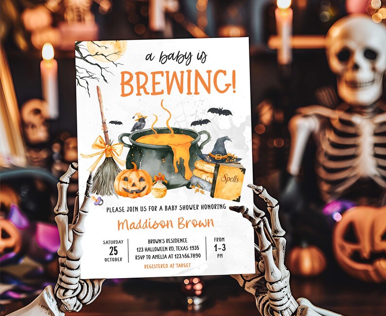 A person holding a Halloween-themed baby shower invitation with a skeleton in the background.