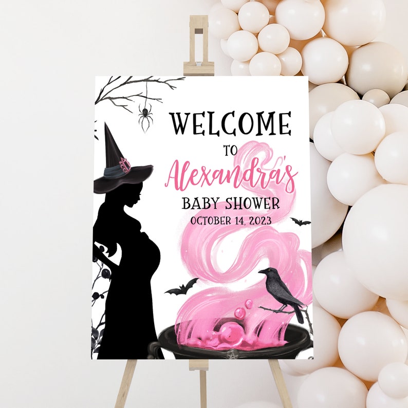 May include: A baby shower welcome sign featuring a silhouette of a pregnant witch wearing a hat. The sign includes the text "Welcome to Alexandra's Baby Shower October 14, 2023" with pink accents and a cauldron.