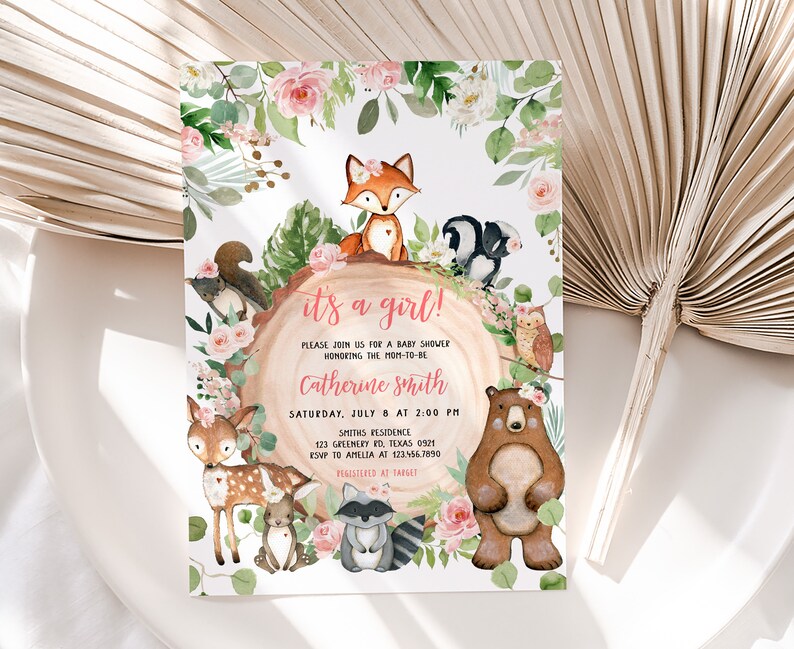 May include: It's a girl! Baby shower invitation with a woodland theme. The invitation features a pink and green floral border with a variety of woodland animals, including a fox, a squirrel, a raccoon, a deer, a bear, and an owl. The text on the invitation reads "It's a girl!" and includes the date, time, and location of the baby shower.