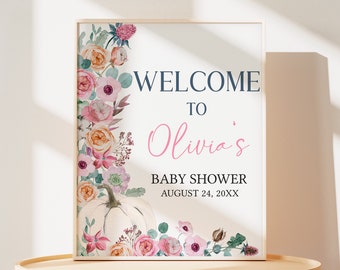 Puede incluir: Un letrero enmarcado para baby shower con detalles florales. El letrero dice "WELCOME TO Olivia's BABY SHOWER" con la fecha. El diseño presenta una calabaza blanca y un borde de flores rosas, melocotón y verdes.