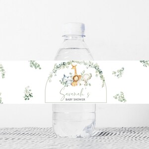 May include: Water bottle label with a watercolor design of a giraffe, lion, and elephant with eucalyptus leaves. The label says "Savannah's Baby Shower".