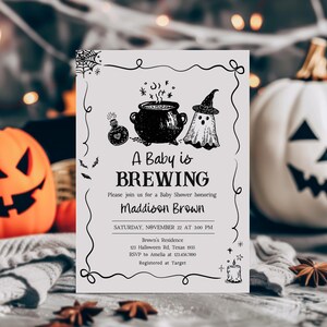 A Halloween-themed baby shower invitation featuring a pumpkin, ghost, and cauldron illustration, with the text "A Baby is BREWING Maddison Brown" and details about the event.