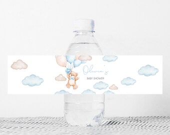 Może przedstawiać: Etykieta na butelkę wody z niebieskim i brązowym misiem trzymającym balony, chmury i tekst "Baby Shower Olivii".