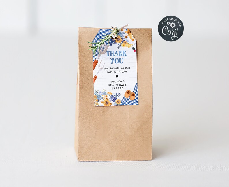 May include: A brown paper gift bag with a blue and white gingham and floral thank you tag. The tag says "Thank You for showering our baby with love" and "Madison's Baby Shower 05.27.23".