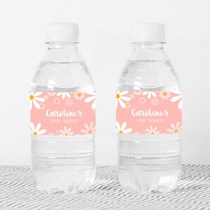 May include: Two clear plastic water bottles with pink and white daisy patterned labels that say "Caroline's Baby Shower".