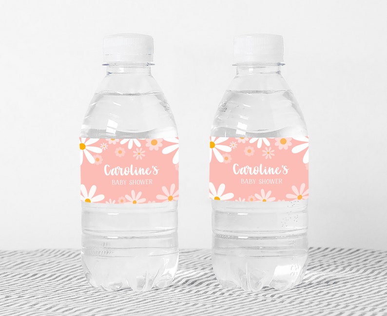 May include: Two clear plastic water bottles with pink and white daisy patterned labels that say "Caroline's Baby Shower".
