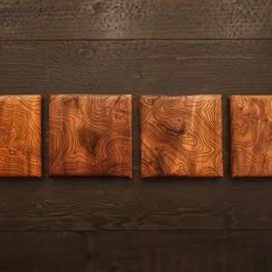 May include: Four wooden coasters with a natural wood grain finish and a unique topographic map design.