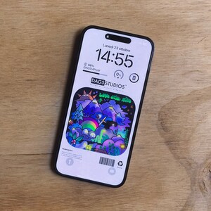 Può includere: Uno smartphone nero con una custodia per telefono colorata che presenta un'illustrazione di cartoni animati di una scena notturna con montagne, stelle e un arcobaleno. La custodia del telefono ha il testo "LOVE STILL ALIVE" e il logo "DAGS STUDIOS".