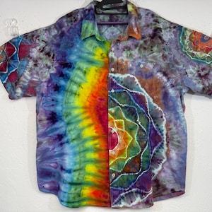 May include: A short-sleeved button-down shirt with a vibrant tie-dye pattern. The shirt features a kaleidoscope of colors, including red, orange, yellow, green, blue, and purple. The design is symmetrical, with a central spiral motif. The shirt has a collar and two chest pockets.