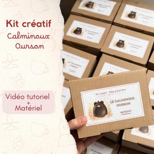 Può includere: Una scatola di kit creativo con il testo "Kit créatif Calminoux Ourson". La scatola presenta un'etichetta con un'illustrazione di orso dei cartoni animati e il testo "LE CALMINOUX OURSON". L'immagine include anche il testo "Vidéo tutoriel + Matériel".