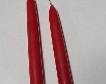 May include: Two red taper candles with white wicks, tied together with a white string.