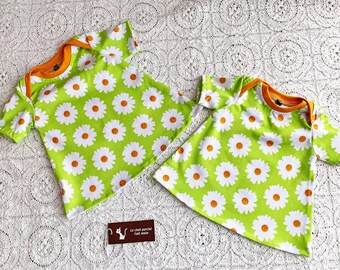 Robe trapèze enfant manches courtes en jersey coton extensible encolure américaine fond vert  larges marguerites blanches et orange brûlée