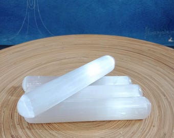 Puede incluir: Un conjunto de cuatro varitas de selenita blanca, apiladas una encima de la otra, sobre una superficie de madera. Las varitas son lisas y pulidas, con una apariencia ligeramente translúcida.