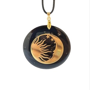 May include: Black pendant necklace with a gold sun and moon design. The pendant is round and has a black cord.