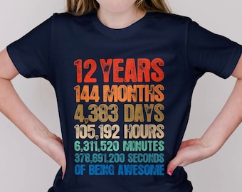 Puede incluir: Una camiseta azul marino con un gráfico de estilo vintage que dice "12 Years 144 Months 4,383 Days 105,192 Hours 6,311,520 Minutes 378,691,200 Seconds of Being Awesome".