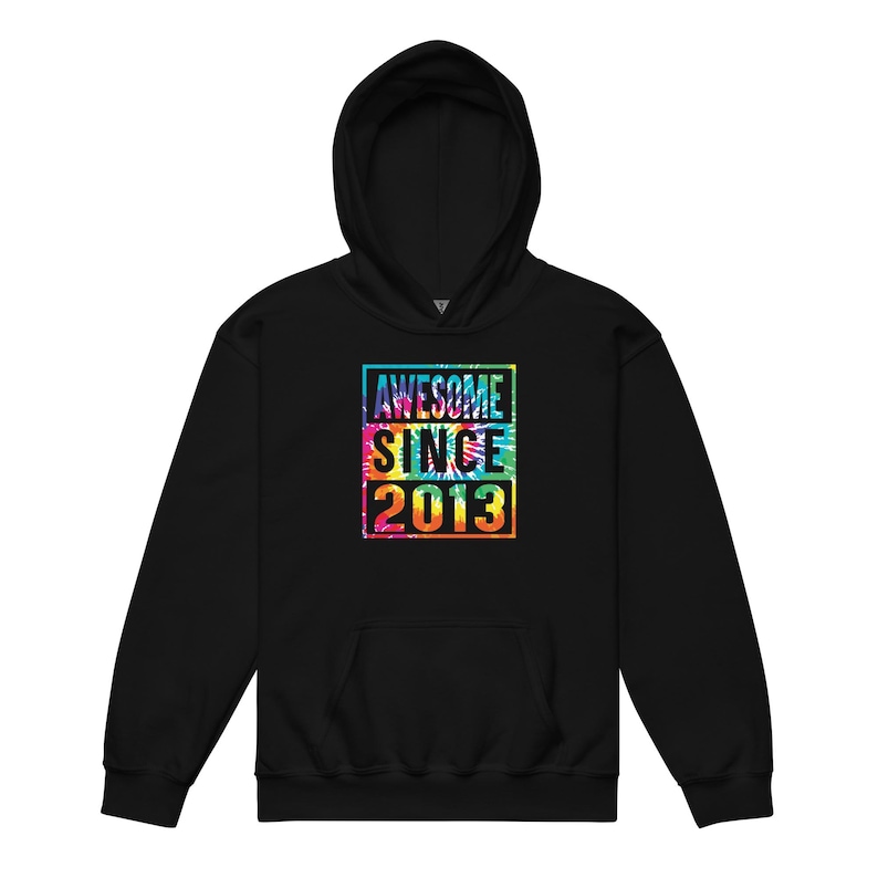 May include: Black hooded sweatshirt with a front pocket and drawstring. The front features a colourful tie-dye square with the words "AWESOME SINCE 2013" in white. The hoodie has a hood and long sleeves.