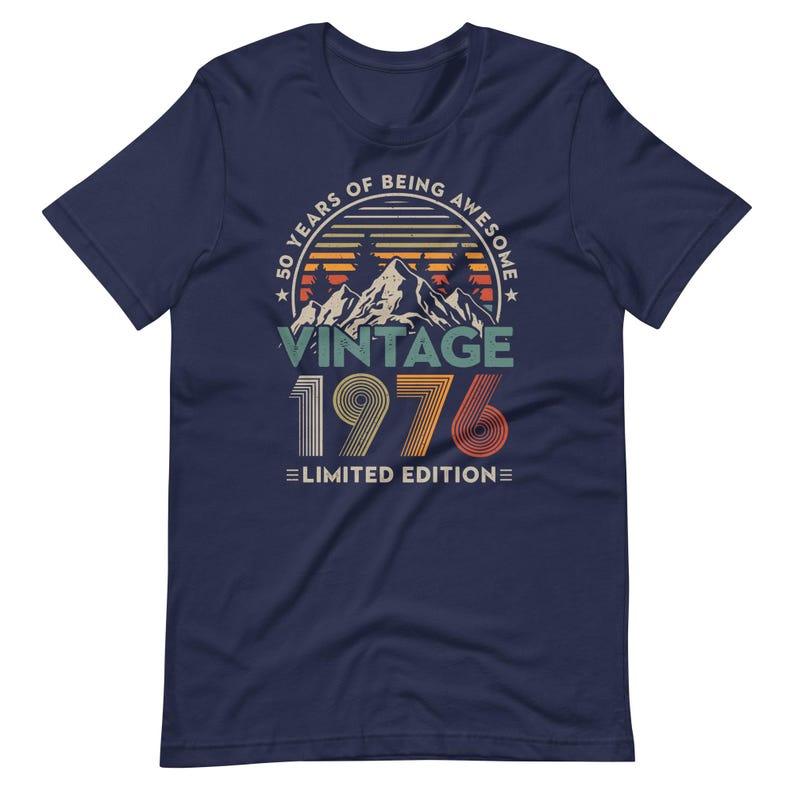 May include: Navy blue t-shirt with a vintage design. The graphic includes the text "50 YEARS OF BEING AWESOME" in a circular design, with "VINTAGE 1976 LIMITED EDITION" below a mountain scene.