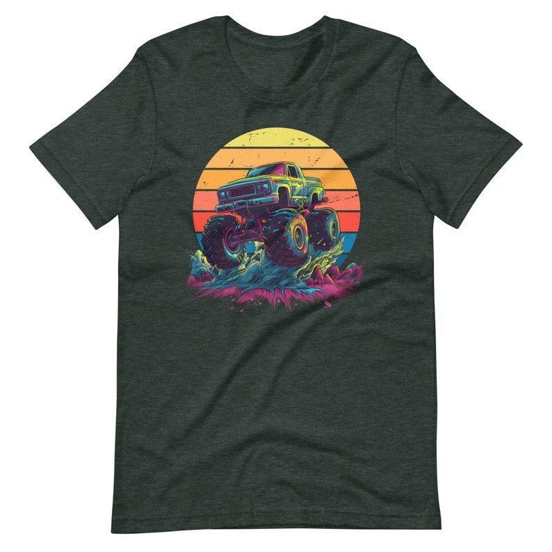 May include: Dark grey t-shirt with a vibrant graphic of a monster truck leaping. The design incorporates a retro sunset in yellow, orange, and red hues. The truck is blue and green, with oversized tyres, set against a splash of colourful water.