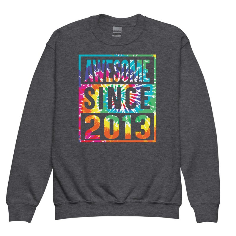 May include: A dark grey sweatshirt featuring the text "AWESOME SINCE 2013" in a vibrant tie-dye pattern. The text is enclosed within a rectangular border. The sweatshirt has a crew neck and long sleeves.