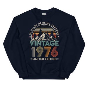 May include: Navy blue sweatshirt with a vintage design. The graphic includes the text "50 YEARS OF BEING AWESOME" above "VINTAGE 1976 LIMITED EDITION" with a mountain and sunset scene.