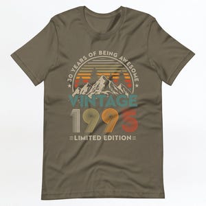 May include: A brown t-shirt with a vintage-style graphic that says "30 Years of Being Awesome Vintage 1995 Limited Edition". The graphic features a mountain range with a sunset behind it.