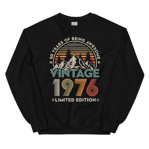 May include: Black sweatshirt with a vintage design. The graphic includes the text "50 YEARS OF BEING AWESOME" in a circular arc, with "VINTAGE 1976 LIMITED EDITION" below a mountain and tree illustration.