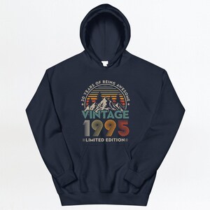 May include: Navy blue hooded sweatshirt with a vintage 1995 design. The graphic features a sunset mountain scene with the text "30 Years of Being Awesome Vintage 1995 Limited Edition".