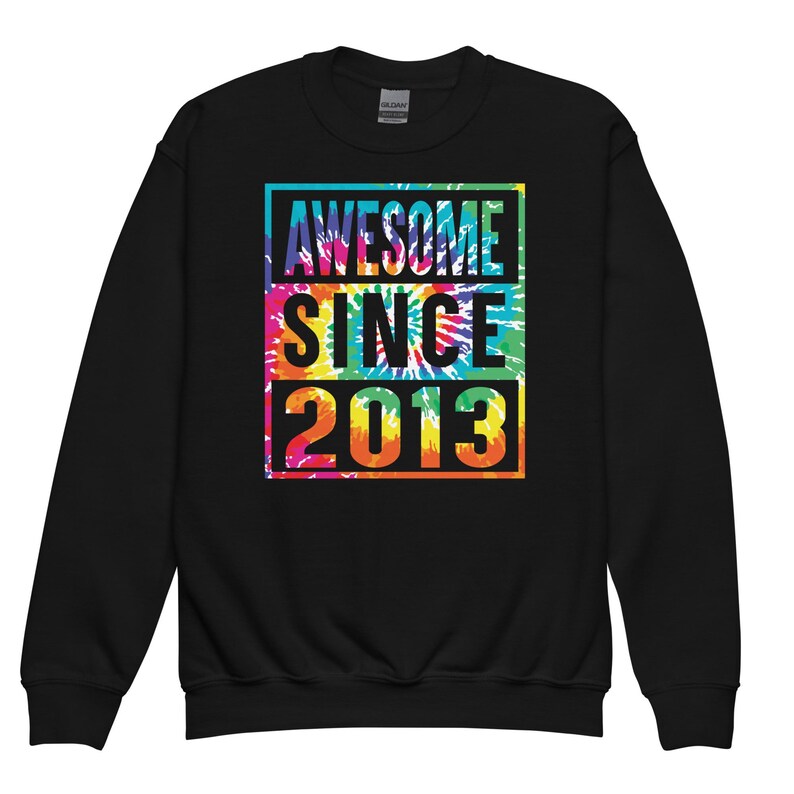 May include: Black sweatshirt featuring the text "AWESOME SINCE 2013" in a vibrant tie-dye pattern. The text is enclosed within a black rectangular frame. The sweatshirt is a Gildan brand.