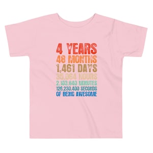 May include: A light pink toddler t-shirt with a retro design. The design includes the text "4 YEARS, 48 MONTHS, 1,461 DAYS, 35,064 HOURS, 2,103,840 MINUTES, 126,230,400 SECONDS OF BEING AWESOME" in various colors.