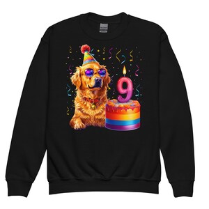 May include: Black sweatshirt featuring a golden retriever wearing sunglasses and a party hat. A birthday cake with a lit candle in the shape of the number 9 is next to the dog. Colorful confetti and streamers are in the background.