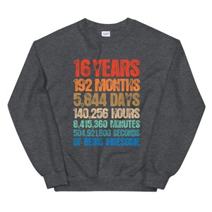 May include: A dark heather gray crewneck sweatshirt featuring a multi-colored graphic print with the text: 16 YEARS, 192 MONTHS, 5,844 DAYS, 140,256 HOURS, 8,415,360 MINUTES, 504,921,600 SECONDS OF BEING AWESOME in a stacked, retro-style font.