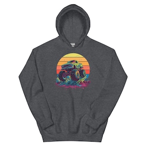 May include: Dark grey hoodie with a colourful graphic of a monster truck set against a sunset. The design shows a detailed truck with large wheels, against a vibrant orange, yellow, and red sunset. The hoodie has a drawstring hood.