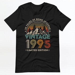 May include: Black t-shirt with a vintage 1995 design. The design features a mountain range with a sunset behind it and the text "30 Years of Being Awesome Vintage 1995 Limited Edition".