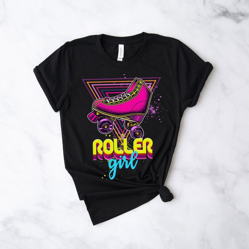 May include: Black t-shirt with a neon pink roller skate graphic and purple and yellow accents. The words "ROLLER girl" are printed below the skate in yellow and teal. The design includes a neon triangle.