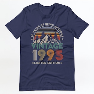 May include: Navy blue t-shirt with a vintage-style graphic design. The graphic features a mountain range with a sunset behind it and the text "30 Years of Being Awesome Vintage 1995 Limited Edition".