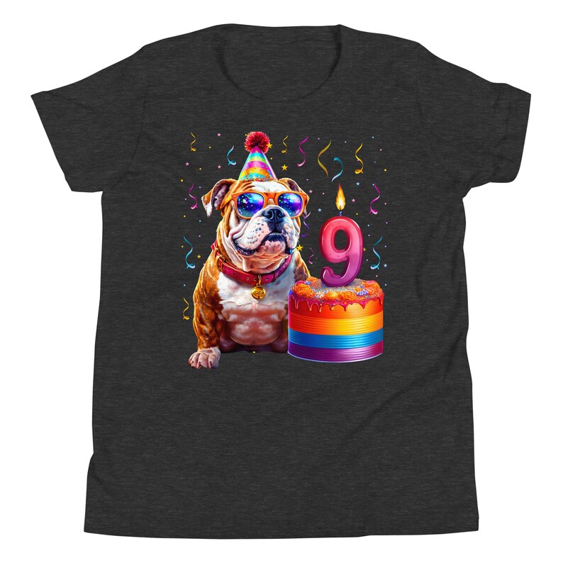 May include: Dark gray t-shirt featuring a colorful illustration of a bulldog wearing sunglasses and a party hat. The bulldog is next to a birthday cake with a number 9 candle, with confetti and streamers in the background.