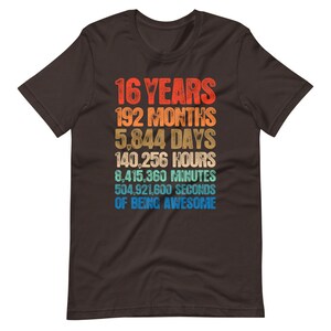 May include: A dark brown short-sleeve t-shirt featuring a multi-colored graphic with the text: 16 YEARS, 192 MONTHS, 5,844 DAYS, 140,256 HOURS, 8,415,360 MINUTES, 504,921,600 SECONDS OF BEING AWESOME, displayed in a stacked, retro-style font.