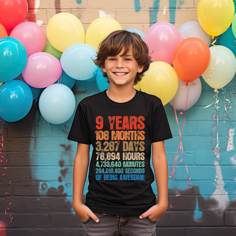 May include: A black t-shirt with a colorful graphic that says "9 Years, 108 Months, 3,287 Days, 78,894 Hours, 4,733,640 Minutes, 284,018,400 Seconds of Being Awesome".