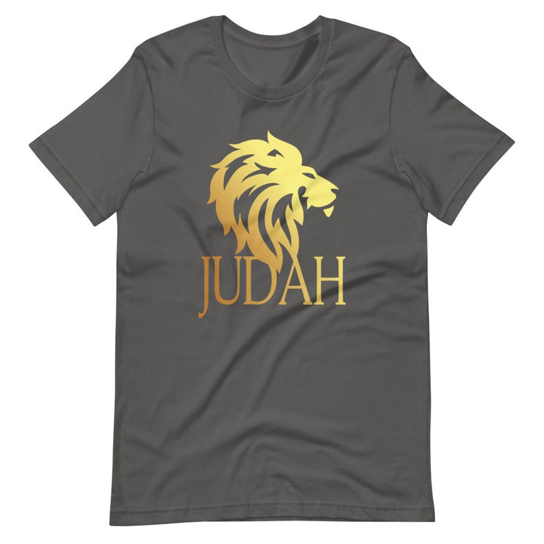 Op de afbeelding: Donkergrijs t-shirt met een gouden leeuw afbeelding en het woord "JUDAH". Het leeuwenontwerp is gedetailleerd en gestileerd, met een vloeiende manen. De tekst is vetgedrukt en zonder schreef.