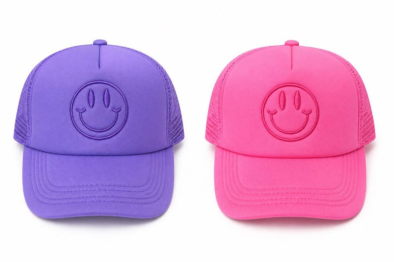 K&ouml;nnte beinhalten: Zwei Baseballkappen, eine lila und eine rosa, jeweils mit einem Smiley-Gesicht-Design. Die Kappen haben einen Mesh-R&uuml;cken und einen gebogenen Schirm. Das Smiley-Gesicht ist auf der Vorderseite jeder Kappe gestickt.