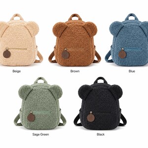 Puede incluir: Cinco mochilas con forma de oso de peluche en beige, marr&oacute;n, azul, verde salvia y negro. Cada mochila tiene un bolsillo frontal con cremallera y una peque&ntilde;a etiqueta redonda marr&oacute;n. Las mochilas tienen orejas de oso en la parte superior y correas ajustables.