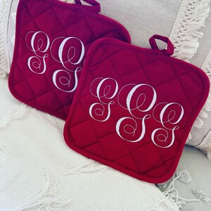 May include: Two red quilted pot holders with white embroidered initials "SSS".