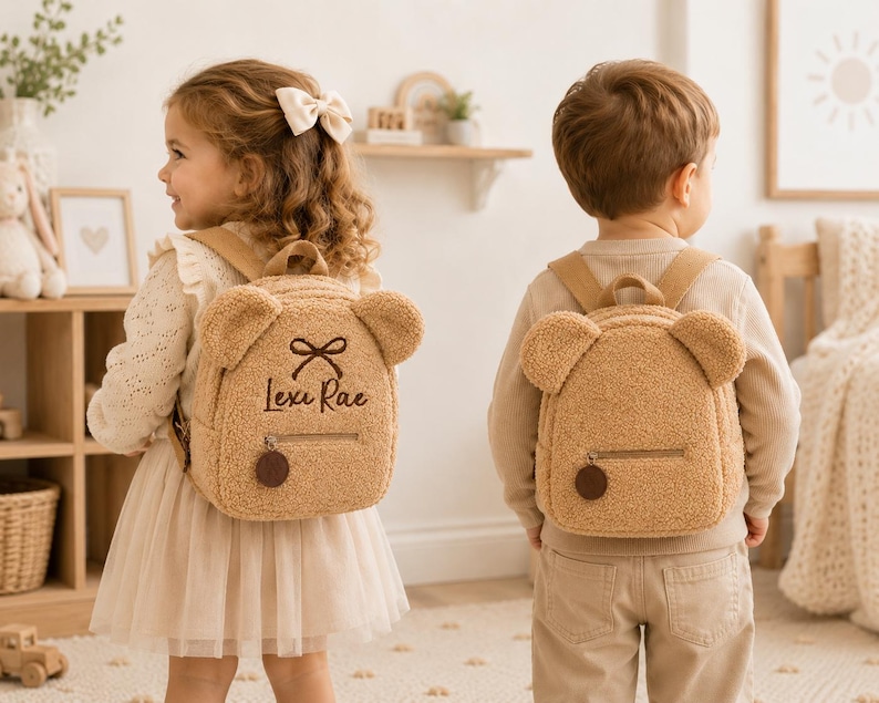 Puede incluir: Dos ni&ntilde;os con mochilas de osito de peluche marrones a juego. Las mochilas tienen orejas de oso, un lazo y el nombre "Lexi Rae" bordado en una. Las mochilas tienen cierre de cremallera y un charm redondo marr&oacute;n.