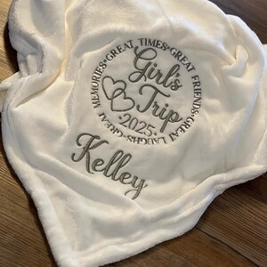 May include: White plush blanket with embroidered text that reads "Memories Great Times Great Friends Great Laughs Great Girl's Trip 2025 Kelley".