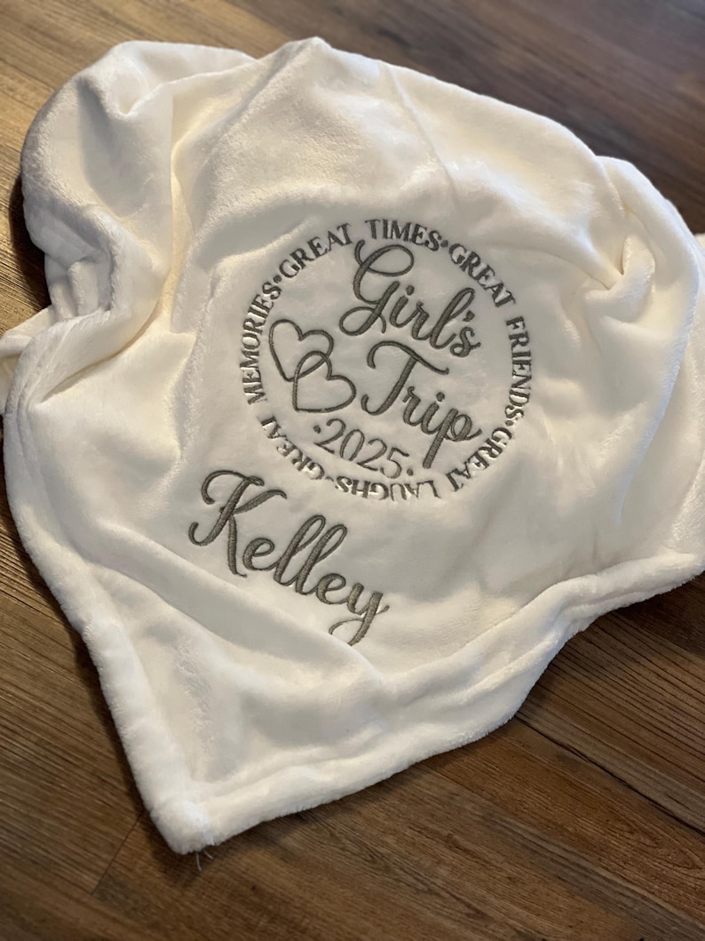 May include: White plush blanket with embroidered text that reads "Memories Great Times Great Friends Great Laughs Great Girl's Trip 2025 Kelley".