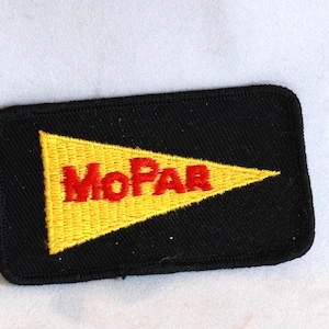 May include: A rectangular black embroidered patch featuring a yellow pennant-shaped design in the center. The word MOPAR is stitched in red capital letters across the yellow pennant. The patch has a black stitched border around the entire edge.