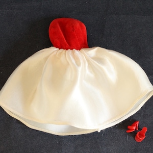 May include: A white satin doll dress with a red velvet bodice and matching red shoes.