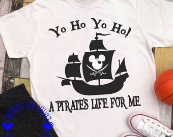 May include: White t-shirt with a black silhouette of a pirate ship with a Mickey Mouse head on the sail. The text "Yo Ho Yo Ho! A Pirate's Life For Me" is printed on the shirt.