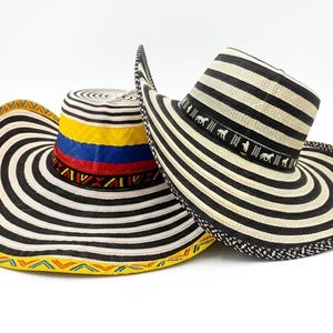 May include: Two straw hats with wide brims. One hat features black and white stripes with a colorful band and a yellow and orange patterned brim. The other hat has black and white stripes and a black band with white horse figures.